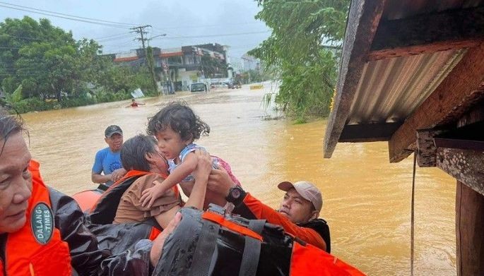 This handout photo taken on Nov. 21, 2023 and received from the Philippine Coast Guard on Nov. 22, 2023 shows coast guard personnel evacuating a child from a flooded home due to heavy rains at a village in Catarman town, Northern Samar, central Philippines.